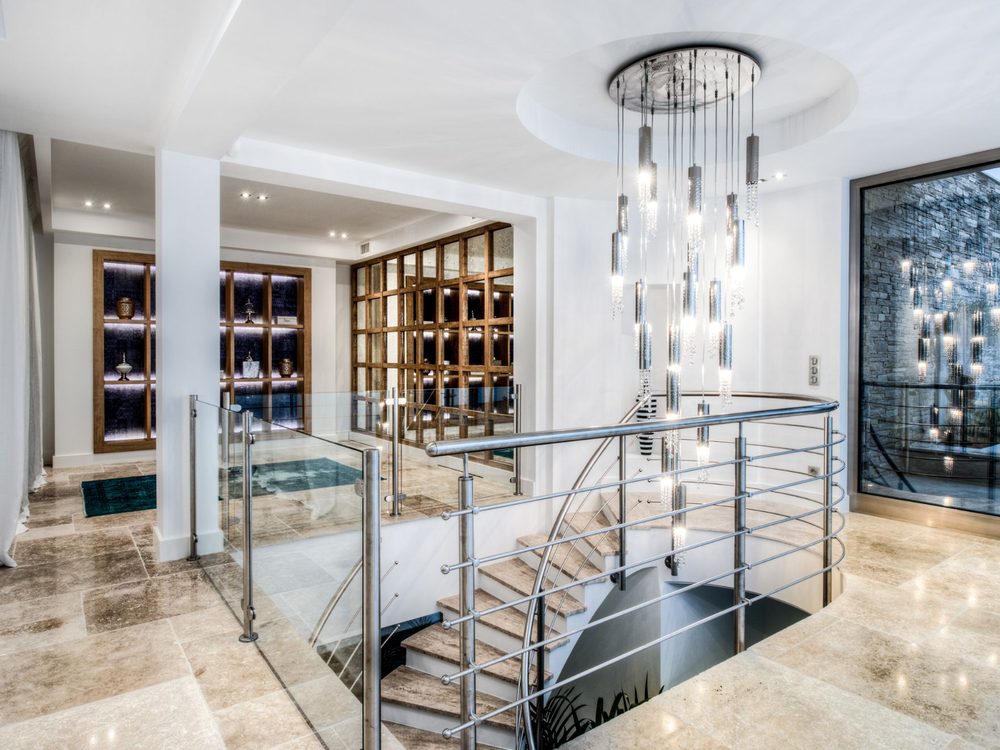 Palier et escalier en travertin sous un lustre en cristal